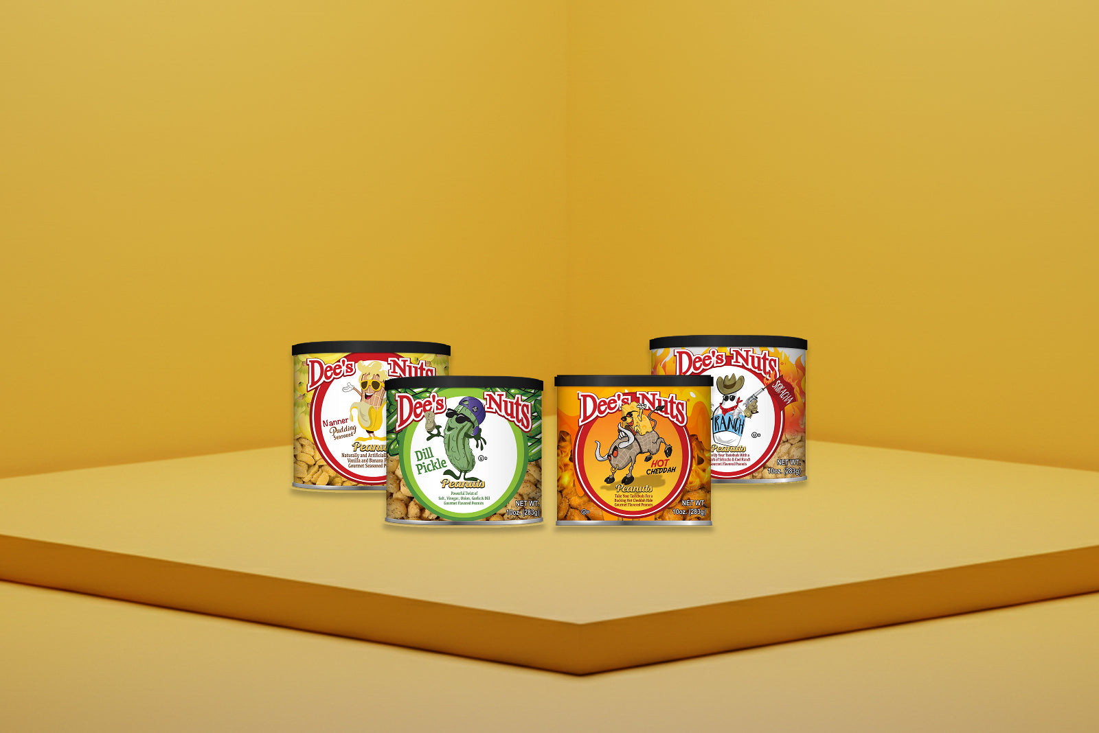 Five Dee’s Nuts gourmet peanut cans—Dill Pickle, Hot Cheddah, Nanner Pudding, Ranch & Sriracha, and Sweet Southern BBQ—displayed on a yellow podium with a yellow backdrop.