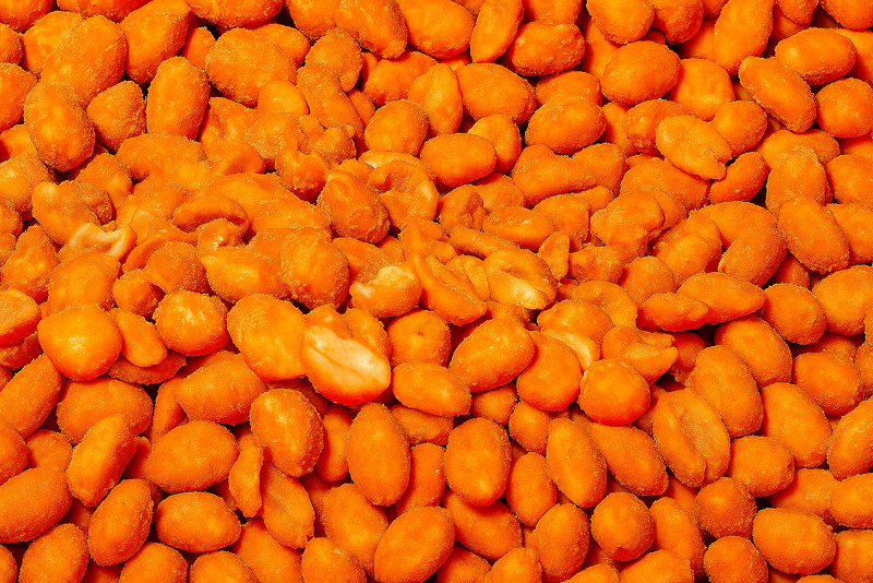 Close-up of crunchy orange-coated peanuts, showing a textured surface with seasoning.